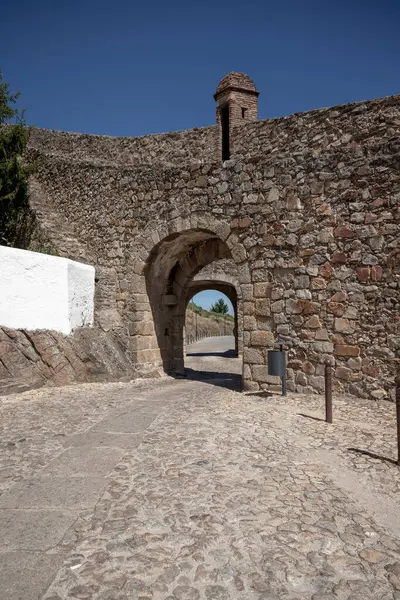 Portekiz 'in Marvao kasabasındaki tarihi taş kapı, açık bir yaz gününde çekilmiş, mimari mirası ve çevresindeki ortaçağ duvarları sergilenmektedir.