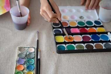Bir çocuk, kağıt üzerinde renkli gökkuşağı temalı sanat eserleriyle suluboya resim yapar, iyi motor beceriler, yaratıcılık ve özerklik geliştirir..