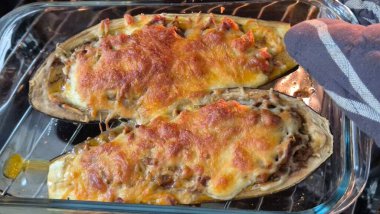 Patlıcan dolması, dana eti ve erimiş peynirle sıcak fırının içinde cam bir kapta pişiyor. Ev mutfağında akşam yemeği ya da öğle yemeği için hazırlanmış lezzetli bir ev yemeği..