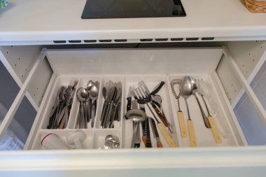 Mutfak çekmecesini çeşitli çatal bıçaklarla kapatın, yemek yaparken kolay erişimi ve organizasyonu gösterin.