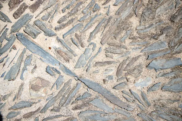 Parlak güneş ışığıyla çekilen geleneksel Portekiz taş kaldırımına yakın çekim, kırsal dokuyu, asimetrik deseni ve eski yolların bölgesel işçiliğini gözler önüne seriyor..