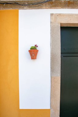 Ağustos 2024 'te Nisa, Portalegre, Alentejo, Portekiz' de çekilen bu fotoğraf, büyüleyici bir köy sokağındaki beyaz boyalı bir duvarı çiçek desenleriyle süsleyen geleneksel kil çömlekleri vurguluyor..