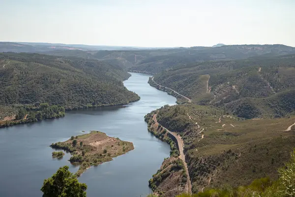 Ağustosta yemyeşil tepelerden akan kıvrımlı Tejo Nehri 'nin nefes kesici hava manzarası. Portekiz, Vila Velha de Rodao 'daki geniş manzaranın sakin ve panoramik görüntüsü.
