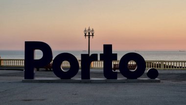 Foz do Douro, Porto, Portekiz 'de günbatımı. İkonik Porto 'nun silueti. Atlantik Okyanusu 'nun kıyısında, Pastel gökyüzü, uzak gemiler ve günün sonunu gösteren sakin sular..