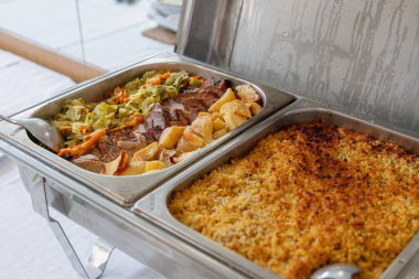 Açık büfe öğle yemeği bir yemek organizasyonunda servis edilir. Sıcak yemek tabakları kızarmış patates ve sebzeli bir et yemeği ve fırında balık yemeği içerir. Toplamak için ideal.