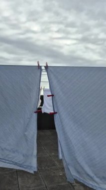 Bulutlu bir yaz günü öğleden sonra rüzgarda dalgalanan çarşaflar çatıdaki çamaşır ipine iğnelendi. Çamaşırlar özgürce dans eder doğa kurudukça..