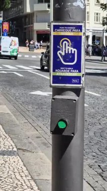Porto, Portekiz - 17 Temmuz 2025: Bir adam caddede yaya geçidi tuşuna basıyor. Şehir taşımacılığı güvenliği: yeşil ışık yakmak için ıkın ve yoğun bir kavşakta güvenli bir şekilde geçmek için bekleyin.