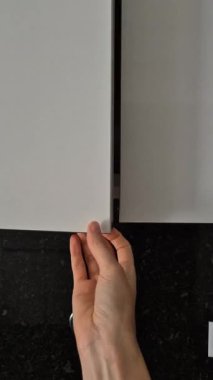 Bir insan, düzenli bir mutfak dolabından beyaz tabakları alıp günlük ev işleri yapar. Öğle yemeği ya da akşam yemeği için sofra hazırlamak gibi. Yakın plan..