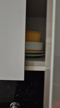 Bir insan, düzenli bir mutfak dolabından beyaz tabakları alıp günlük ev işleri yapar. Öğle yemeği ya da akşam yemeği için sofra hazırlamak gibi. Yakın plan..