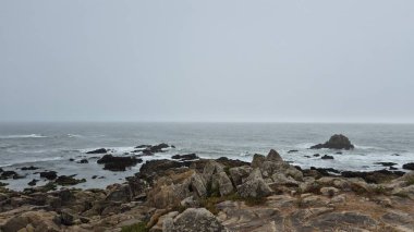 Portekiz 'in Matosinhos bölgesindeki Leca da Palmeira' daki kayalık Atlantik kıyısında dalgalar engebeli bir deniz gününde engebeli taşlara çarpıyor. Dramatik deniz manzarası doğanın gücünü ve kıyı yalnızlığını çağrıştırıyor..