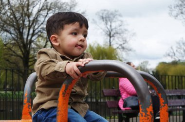 Şirin Asyalı Pakistanlı Bebek İngiltere 'nin Luton kasabasındaki Savaş Parkı' nda eğleniyor.