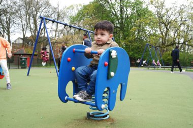 Şirin Asyalı Pakistanlı Bebek İngiltere 'nin Luton kasabasındaki Savaş Parkı' nda eğleniyor.