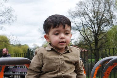Şirin Asyalı Pakistanlı Bebek İngiltere 'nin Luton kasabasındaki Savaş Parkı' nda eğleniyor.