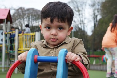 Şirin Asyalı Pakistanlı Bebek İngiltere 'nin Luton kasabasındaki Savaş Parkı' nda eğleniyor.