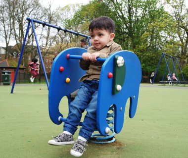 Şirin Asyalı Pakistanlı Bebek İngiltere 'nin Luton kasabasındaki Savaş Parkı' nda eğleniyor.
