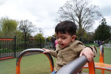 Şirin Asyalı Pakistanlı Bebek İngiltere 'nin Luton kasabasındaki Savaş Parkı' nda eğleniyor.