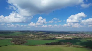 Paragliderler güzel güneşli ve kısmen bulutlu bir günde İngiliz kırsalında uçuyorlar.