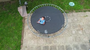 Baby Boy, Drone 'un kamerasının altında, bahçede trambolinde poz veriyor.