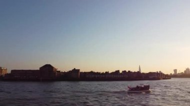 Günbatımında Londra 'nın merkezindeki Thames Nehri' nde tekne. Görüntüler 8 Haziran 2023 'te Canary Wharf London England' da çekildi..