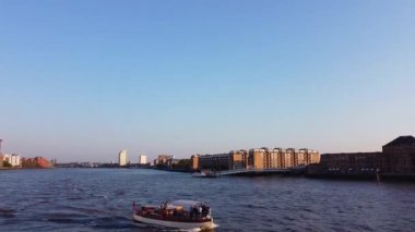 Günbatımında Londra 'nın merkezindeki Thames Nehri' nde tekne. Görüntüler 8 Haziran 2023 'te Canary Wharf London England' da çekildi..