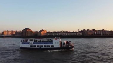 Günbatımında Londra 'nın merkezindeki Thames Nehri' nde tekne. Görüntüler 8 Haziran 2023 'te Canary Wharf London England' da çekildi..