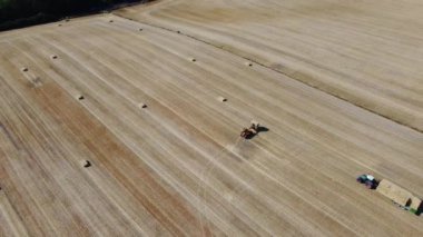 İngiliz tarım çiftliklerinin ve traktörle çalışan makinelerin hava görüntüleri. Hey 'i karadan buğday kestikten sonra yüklüyorlar. Hava Görüntüleri 14 Ağustos 2022 'de Dunstable Downs İngiltere' de çekildi.