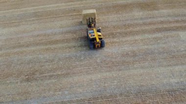 İngiliz tarım çiftliklerinin ve traktörle çalışan makinelerin hava görüntüleri. Hey 'i karadan buğday kestikten sonra yüklüyorlar. Hava Görüntüleri 14 Ağustos 2022 'de Dunstable Downs İngiltere' de çekildi.