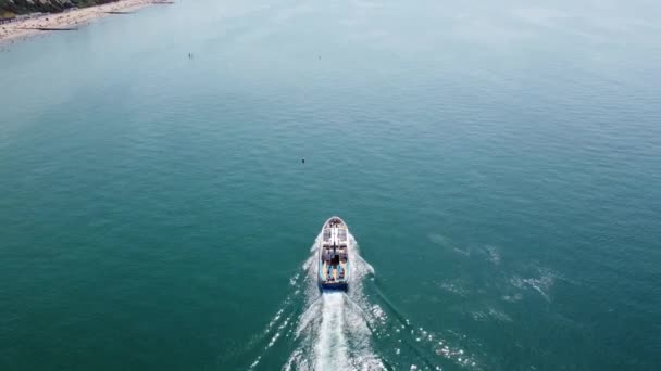 スローモーション英国ボーンマスビーチと海で高速移動スポーツボートの高角度空中映像 夏の美しい暑い日 人々は夏休みを楽しんでいる — ストック動画
