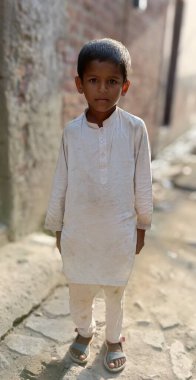 Pakistan 'ın bir köyünde 13-8-23 numaralı sokakta duran fakir bir çocuk.
