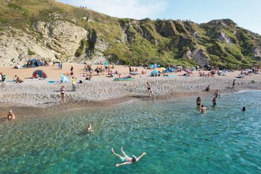 Muhteşem Yüksek Açılı Halk Manzarası İngiltere 'nin Durdle Door Manzaralı Suları' nın Okyanus Sahili 'nde Britanya' nın Kayılarda ve Yüzmede Sıcak Havası 'nın tadını çıkarıyor. Resim 9 Eylül 2023 'te çekildi.
