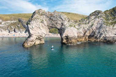 Muhteşem Yüksek Açılı Halk Manzarası İngiltere 'nin Durdle Door Manzaralı Suları' nın Okyanus Sahili 'nde Britanya' nın Kayılarda ve Yüzmede Sıcak Havası 'nın tadını çıkarıyor. Resim 9 Eylül 2023 'te çekildi.