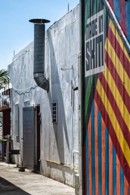 A side alley with a brightly striped wall featuring a large vent pipe, evoking industrial and urban themes clipart