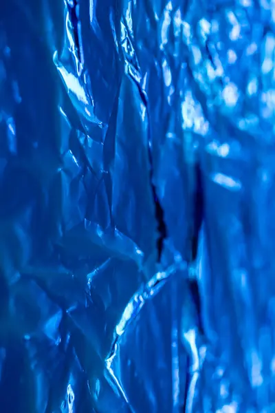 stock image Magnified view showing the intricate texture of crumpled blue foil, highlighting details and reflections