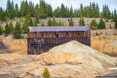 Colorado 'nun göbeğindeki çam ağaçlarının arasında duran eski, yıpranmış bir ahşap maden yapısı doğa ve dağların ortasındaki tarihi endüstriyi sembolize ediyor.