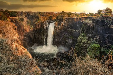 Gün batımında kayalıklar tarafından zarif çerçevelenmiş bir şelale. Resmedilmeye değer ve ruhani atmosferi arttıran altın bir parıltı yayıyor..