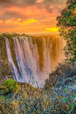 Şelaleler gün batımında dramatik bir şekilde batar. Renkli gökyüzü, doğal güzelliğin ve elementlerin hayranlık uyandıran bir zeminini yaratır..
