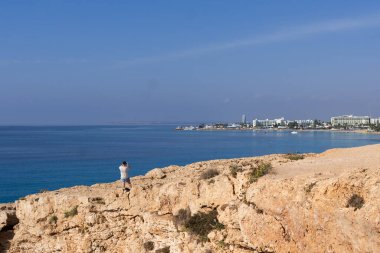Taşları ve taşları olan yaz plajı. Temiz su ve mavi. Adriyatik Denizi 'nin sularındaki taş yığınlarının üzerine kısmen gölge, kısmen güneş ışığı ile aydınlanan devasa mavi kayaların yakınındaki gökyüzüne bak