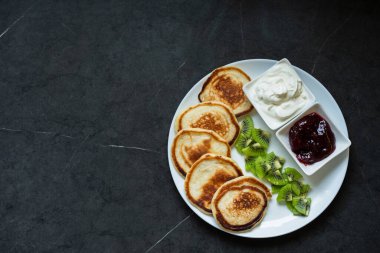 Kiraz reçeli ve kivi parçalarıyla damlayan bir tabak krep. Krep günü.