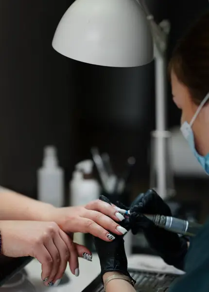 stock image Beautician Salon, Manicure, Nails Polish Procedure. Professional hardware manicure using electric machine in beauty salon. master uses an electric machine to remove nail polish hands during manicure.