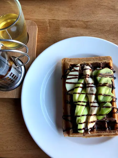 Stock image Morning waffles with green kiwi and fork on a green surface