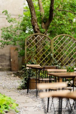 Arka bahçedeki modern salon. Teras evi bitkilerle, ahşap duvarlarla ve koltuklu ve fenerli bir masa. Avluda ya da balkonda rahat bir yer. Bahçe mobilyaları ile ahşap veranda.