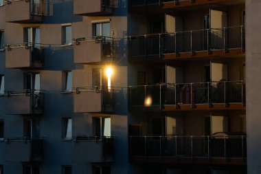 Alçak irtifa manzarası, gün batımında çekilen büyük bir apartmana bakmak. Güneş, bronzlaşma rengi binasının camlarından yansıyor.