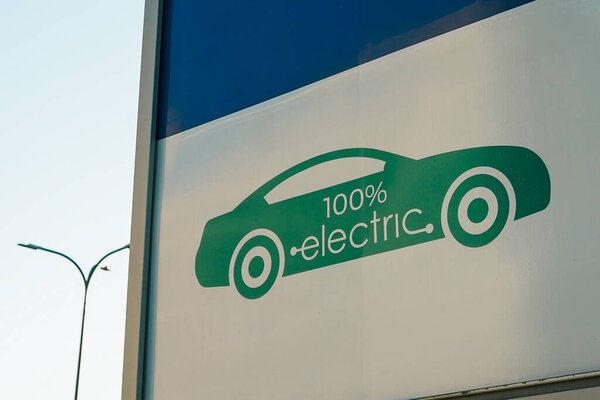 Точка зарядки электромобиля на белом столбе против кирпичного здания