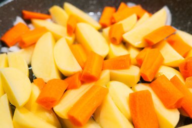 Tavada pişirmek için dilimlenmiş sebzeler. patates, havuç