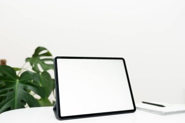 Boş bir tablet ekran, espresso, hesap makinesi ve dokulu bir masa üzerinde kağıt işleriyle düzgün bir ofis düzeni..