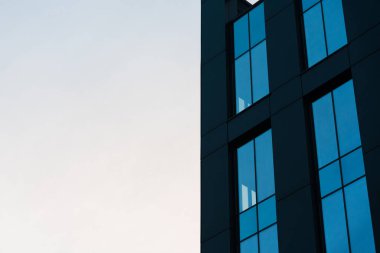 Büyük cam pencereli modern mimari ofis bulutlu mavi gökyüzünü yansıtıyor