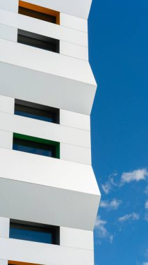 Modern mimari stil ve yaratıcılığın sergilendiği canlı mavi gökyüzüne karşı, geometrik tasarım elementleriyle çağdaş bir yapı cephesi..