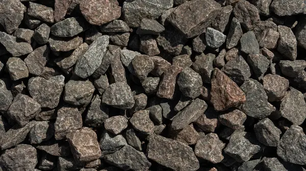 Çeşitli büyüklükteki gri ve kahverengi kayaların ayrıntılı bir görüntüsü kaba dokularını ve doğal desenlerini gözler önüne seriyor..