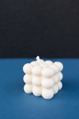 Modaya uygun bir balon küpü mumu mavi arka planda izole edilmiş, ev dekorasyonu veya minimalist tasarım projeleri için mükemmel..