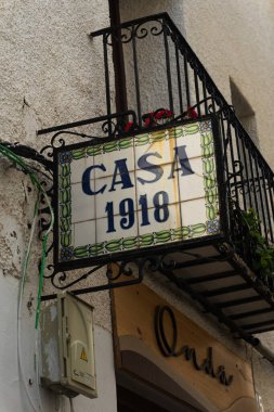 15 Mayıs 2025, İspanya, Guadalest: dekoratif seramik işaretli ev girişi. Kentsel ortamlarda tarihi mimari veya İspanyol ev dış görünüşlerini resmetmek için kullanışlı.